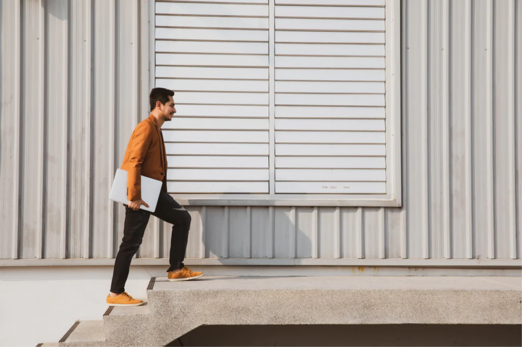 A man holding a laptop, walking up a set of stairs